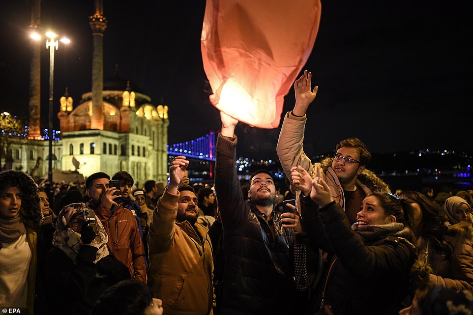 People celebrate the turn of the year in front of the Ortakoy mosque and 15 July Martyrs Bridge near the Bosphorus during new year's celebrations in Istanbul, Turkey, 01 January, 2020