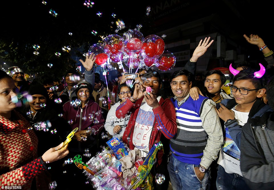 People gather around a vendor blowing bubbles during celebrations to welcome the New Year in a road in Ahmedabad, India, December 31, 2019