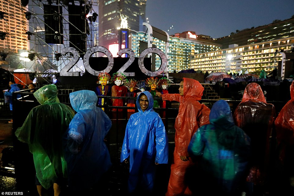 People wearing rain coats gather at Bundaran Hotel Indonesia roundabout as they attend New Year's Eve celebrations in Jakarta