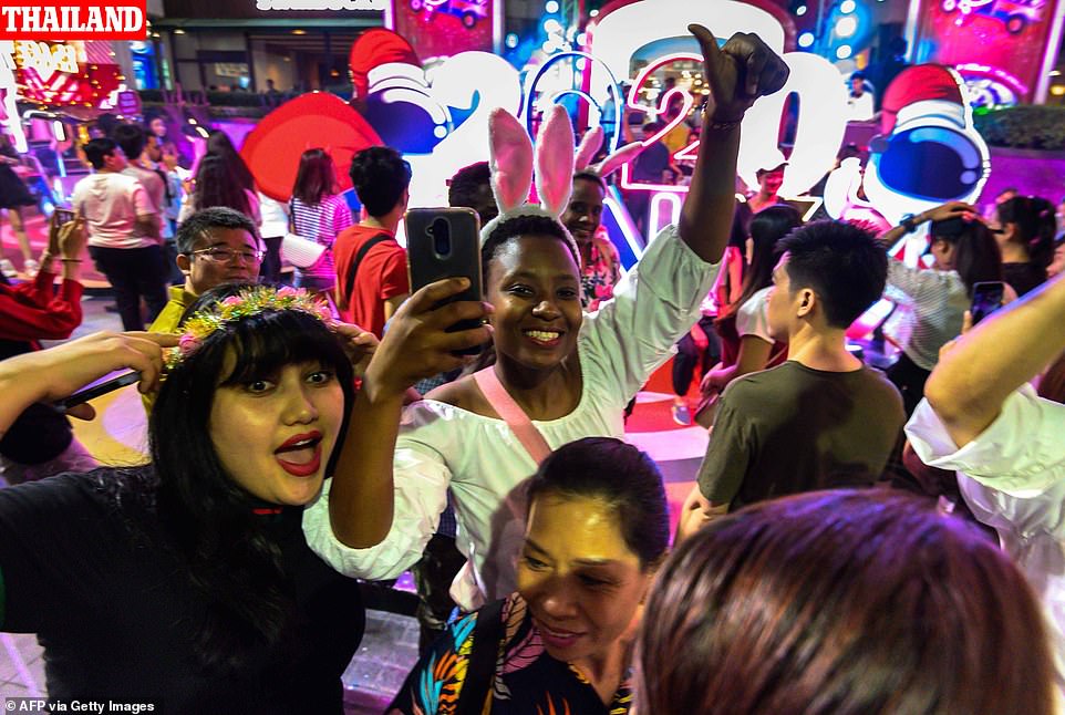 Revellers take a selfie while arriving for a New Year countdown party outside a shopping mall in downtown Bangkok on December 31