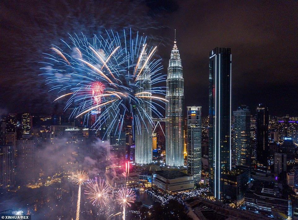 The twin Petronas skyscrapers are temporarily overshadowed by the dazzling display of New Year's Eve pyrotechnics